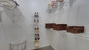 A walk in closet with white shelves and wicker baskets